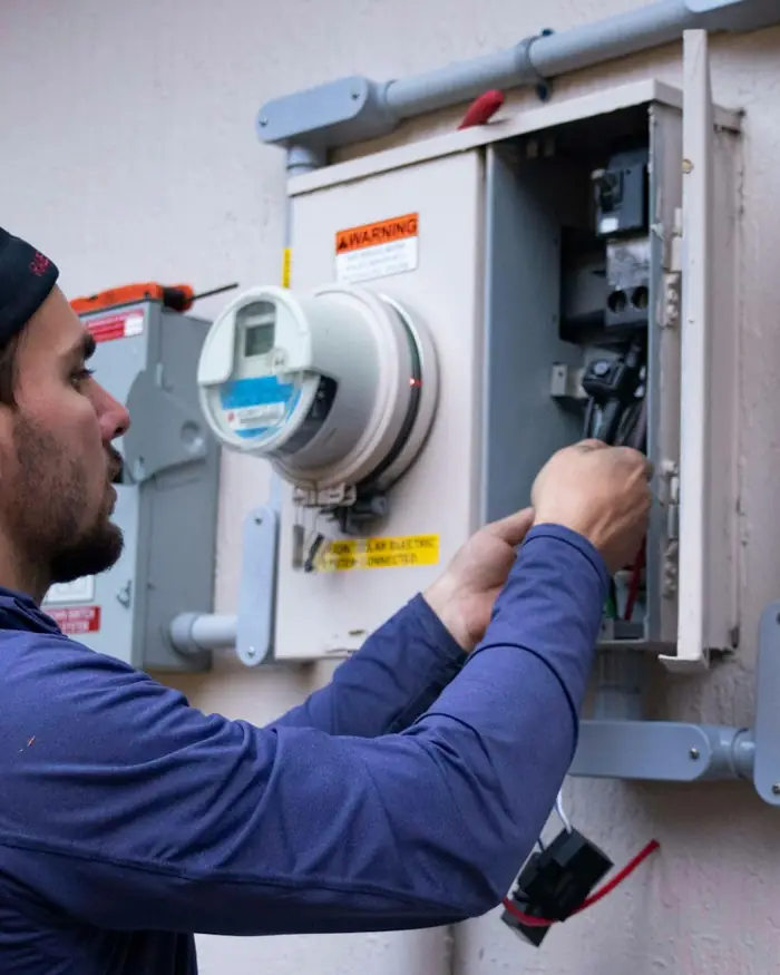 Technician in a blue jacket working on an outdoor electrical panel