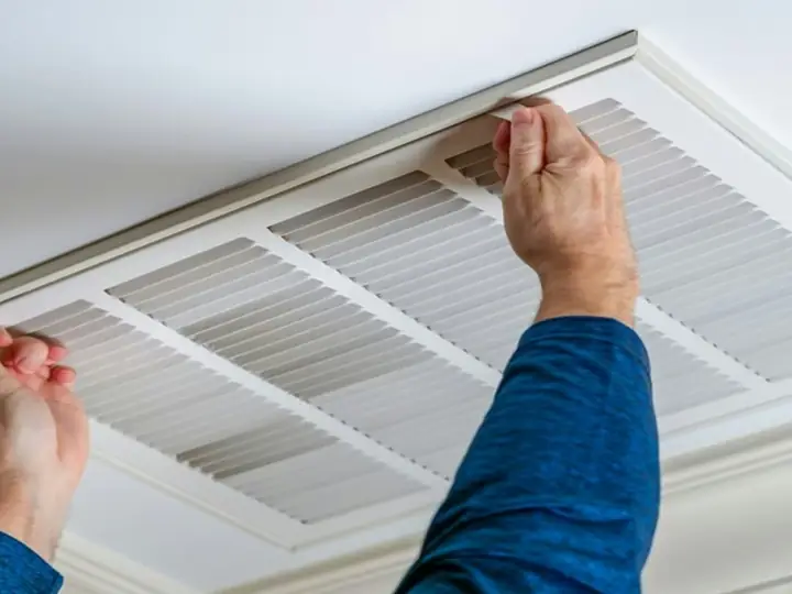 Technician removing a ceiling return air vent cover