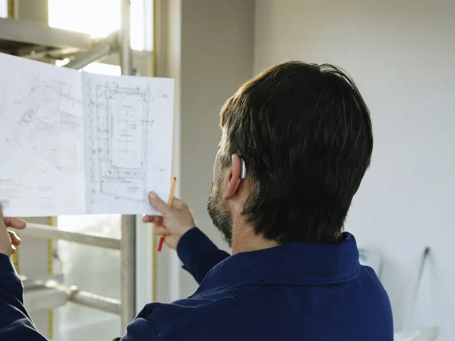 Man reviewing blueprints in a room under construction
