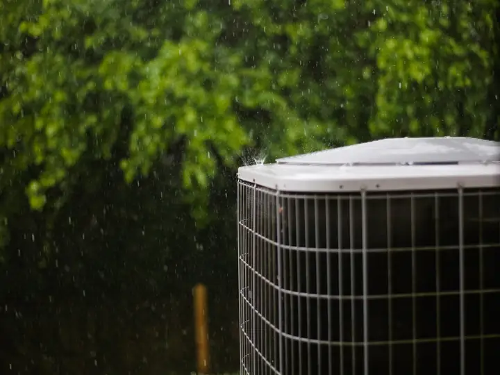 Outdoor air conditioner condenser unit beside green trees