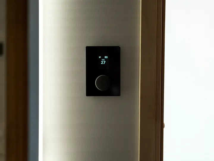 Black smart thermostat mounted on a wall