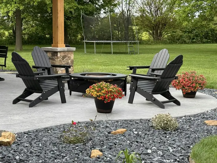 Backyard patio with dark Adirondack chairs around a fire pit