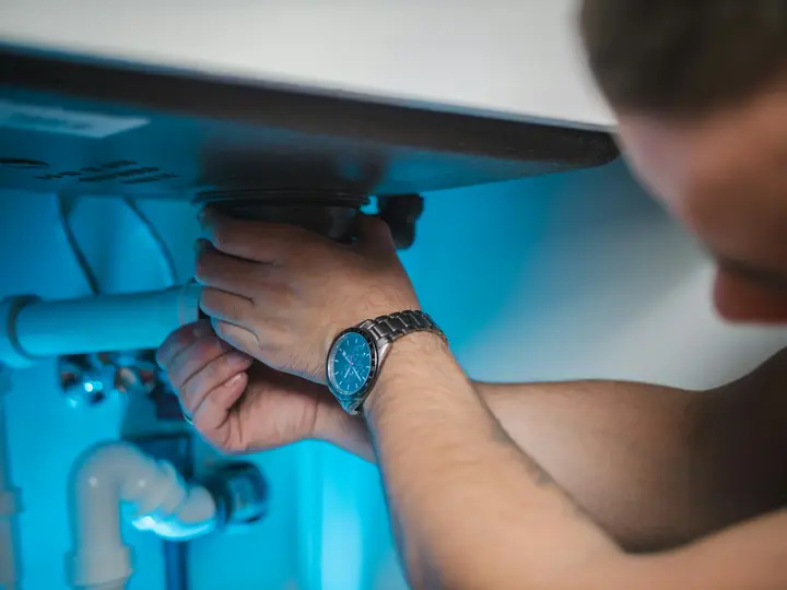 Plumber checking pipe fittings under a sink